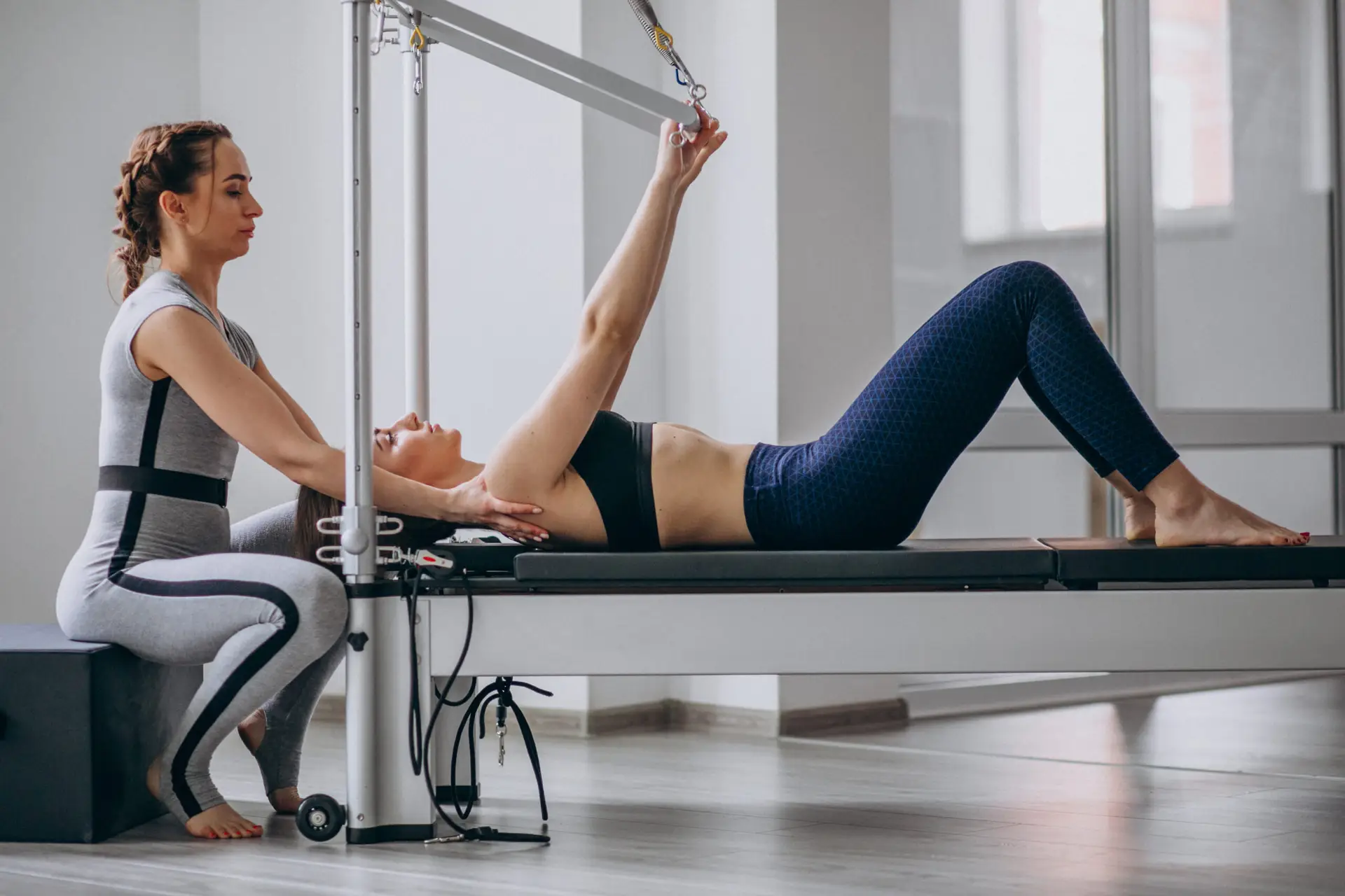 Ana Sayfa 14 Klinik pilates reformer cihazında egzersiz yapan kadın ve eğitmeni